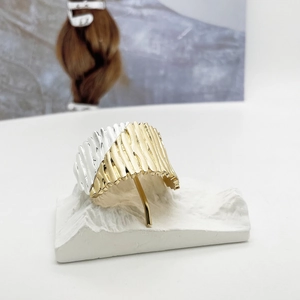 Detail of bicolored gold and silver metal hair clip with geometric pleated texture
