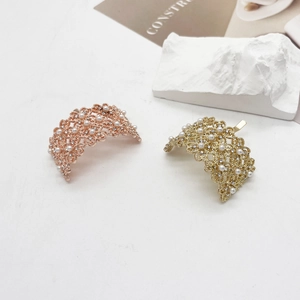 Dettaglio di fermagli per capelli in metallo traforato con perle bianche e strass