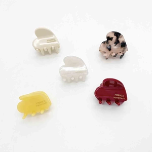 Five assorted heart-shaped acetate hair claws in cream, yellow, red and tortoiseshell patterns