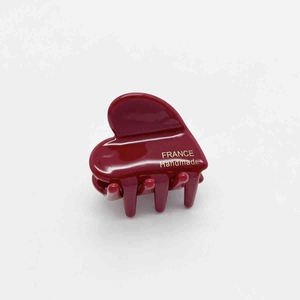 Detail of dark red acetate heart hair clip featuring a gold France Handmade logo