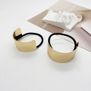 Detail of minimalist gold U-shaped metal hair ties with black elastic bands