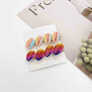 Detailed view of colorful shell hair clips with gradient resin designs on gold metal base