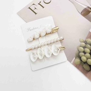 Detailed close-up of shell and pearl hair clip set on a decorative display card