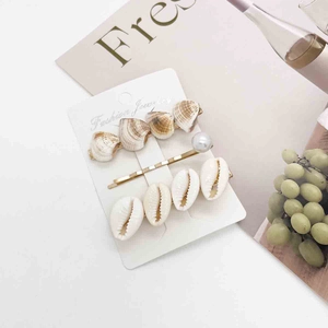 Detail view of 3-piece shell and pearl hair clip set on a minimalist fashion display card