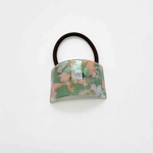 Detail of elegant marble texture acetate U-shape hair tie with green and pink patterns