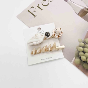 Detailed close-up of seashell and conch hair clip set on a white display card