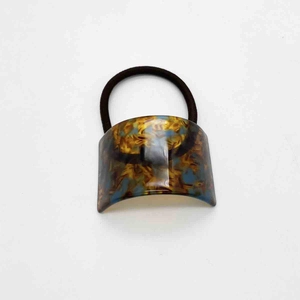 Close-up of elegant tortoiseshell U-shaped acetate decoration on black elastic hair tie