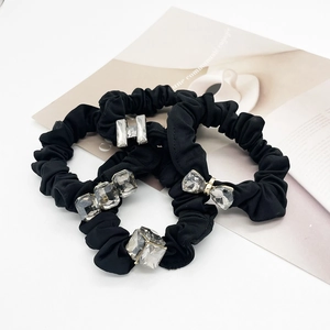 Three black scrunchies with crystal butterfly and letter H decorations on a white background