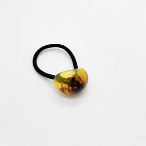 Dettaglio dell'elastico per capelli nero con decoro ovale in resina ambra su bianco