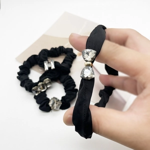 Three elegant black fabric scrunchies with sparkling crystal butterfly and geometric charms