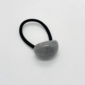 Dettaglio dell'elastico nero con perla in resina lucida effetto marmo grigio per capelli