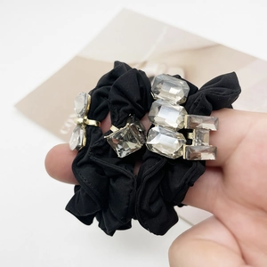 Close-up of black elastic hair ties set with sparkling crystal accents and gold claw setting