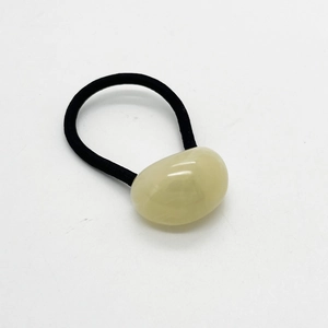 Dettaglio di un elastico nero per capelli con decorazione ovale in resina liscia