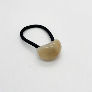 Dettaglio di elastico nero ad alta elasticità con perla in resina ovale beige su bianco