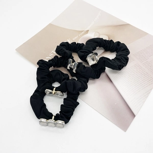 Detail of black fabric hair scrunchies featuring crystal H and square gem accents
