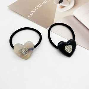 Dettaglio di elastici per capelli con ciondoli a cuore in acrilico e strass luccicanti