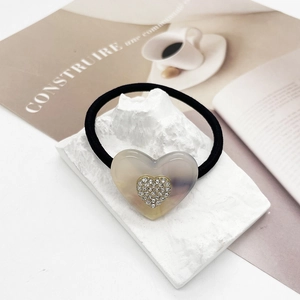 Dettaglio dell'elastico per capelli con cuore in resina marmorizzata e strass