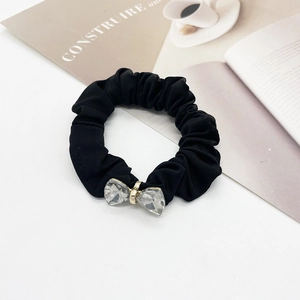 Detailed shot of black scrunchie with crystal butterfly accent and gold buckle