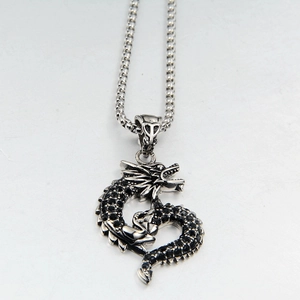 Detail of vintage dragon pendant with black crystal scales on a silver box chain