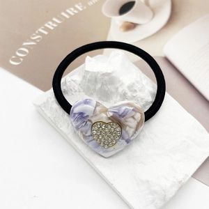 Macro dettagliata di un elastico per capelli a cuore in marmo viola con strass su pietra