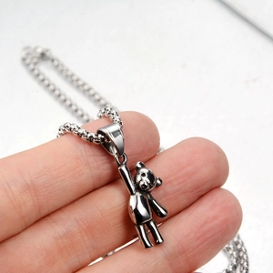 Pendentif ours en acier titane poli tenu en main pour montrer la taille et l'éclat