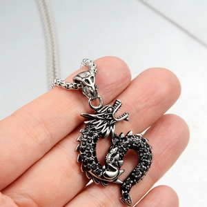 Detailed close-up of a dragon pendant with black rhinestones and a silver bead chain link