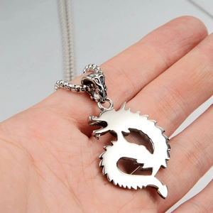 Macro shot of silver dragon pendant necklace in hand showing intricate metalwork