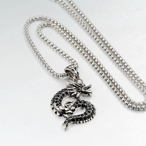 Pendant necklace featuring a silver-colored dragon set with black rhinestones on bead chain