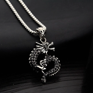 Detailed close-up of a silver dragon pendant with black rhinestones on a box chain