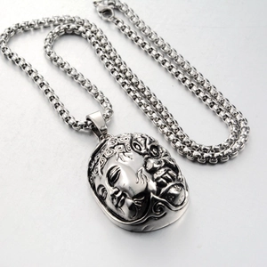 Macro detail of silver stainless steel pendant with intricate Buddha face carving