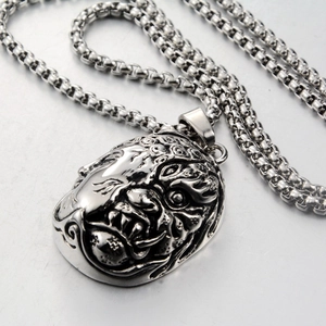 Detailed relief of silver-toned monster mask pendant with blackened vintage effect