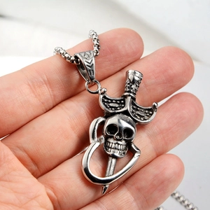 Détail d'un collier punk gothique avec pendentif crâne et épée et cœur évidé sur chaîne à billes