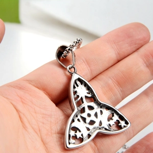 Detail of a silver Celtic knot triangle pendant held in hand showing hollow metalwork