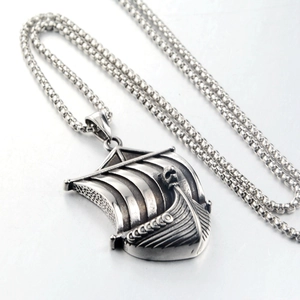Detailed close-up of a vintage Viking ship pendant with intricate skull and sail carvings