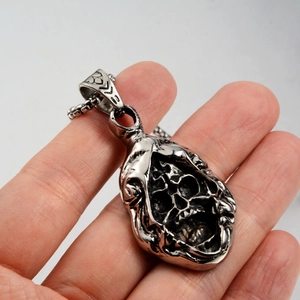 Gothic skull pendant necklace in silver stainless steel held in hand for size context