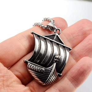Detail of vintage silver Viking longship pendant with dragon head and shield carvings