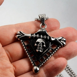 Detail of vintage silver skull triangle pendant with antique finish and box chain