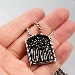 Detail of high relief relief rectangular shield pendant with intricate carving on box chain