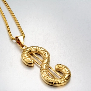 Macro view of gold-plated dollar sign pendant with heart and cross texture details