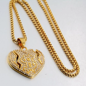 Détail d'un pendentif cœur brisé doré style hip-hop avec signe dollar et zircons