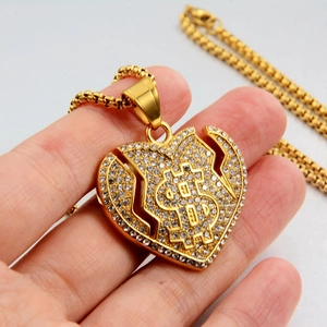 Gros plan du collier hip-hop avec pendentif cœur brisé doré, signe dollar et cristaux brillants