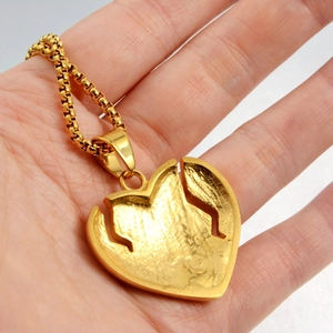 Détail du pendentif cœur dollar doré avec texture mate sur une chaîne à mailles