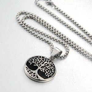 Macro view of stainless steel tree of life pendant featuring intricate hollow engraving