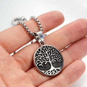 Close-up of a silver Tree of Life pendant in stainless steel held in hand for size reference