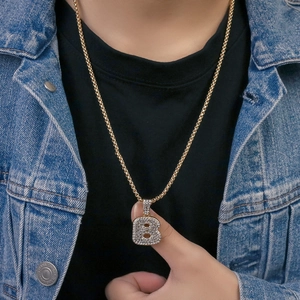 Dettaglio della collana con pendente lettera B dorata e zirconi su giacca di denim
