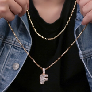 Primo piano della collana con pendente a lettera F dorata e strass luminosi sulla modella