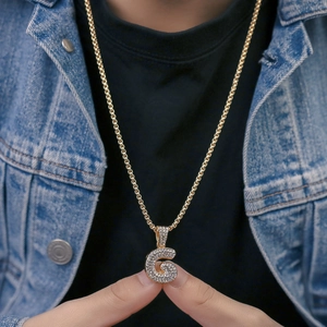 Dettaglio della collana con pendente lettera G dorata e strass su catena a maglie spesse