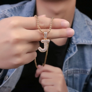 Dettaglio della collana con ciondolo lettera J dorata con zirconi indossata da un modello