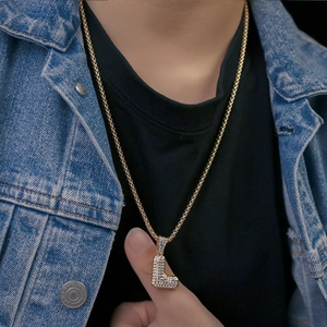 Dettaglio della collana con ciondolo lettera L dorata con strass lucidi indossata