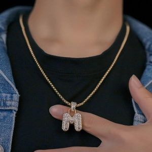 Dettaglio collana con pendente lettera M placcata oro 18K con zirconi indossata da modella
